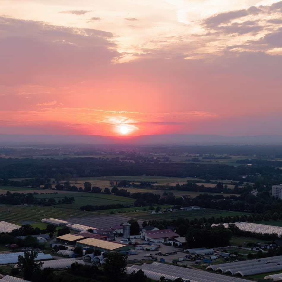Weiterstadt mit Feldern und rotem Sonnenuntergang im Sommer, Drohnenaufnahme