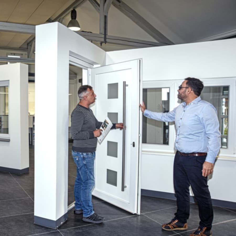 Geschäftsführer Willi Hartmann von Fensterbau Hartmann zeigt einem Kunden eine Haustür.